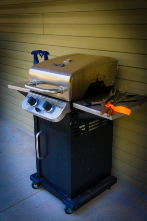 Two-burner gas grill located on the back patio of the house for grilling steaks or chicken.